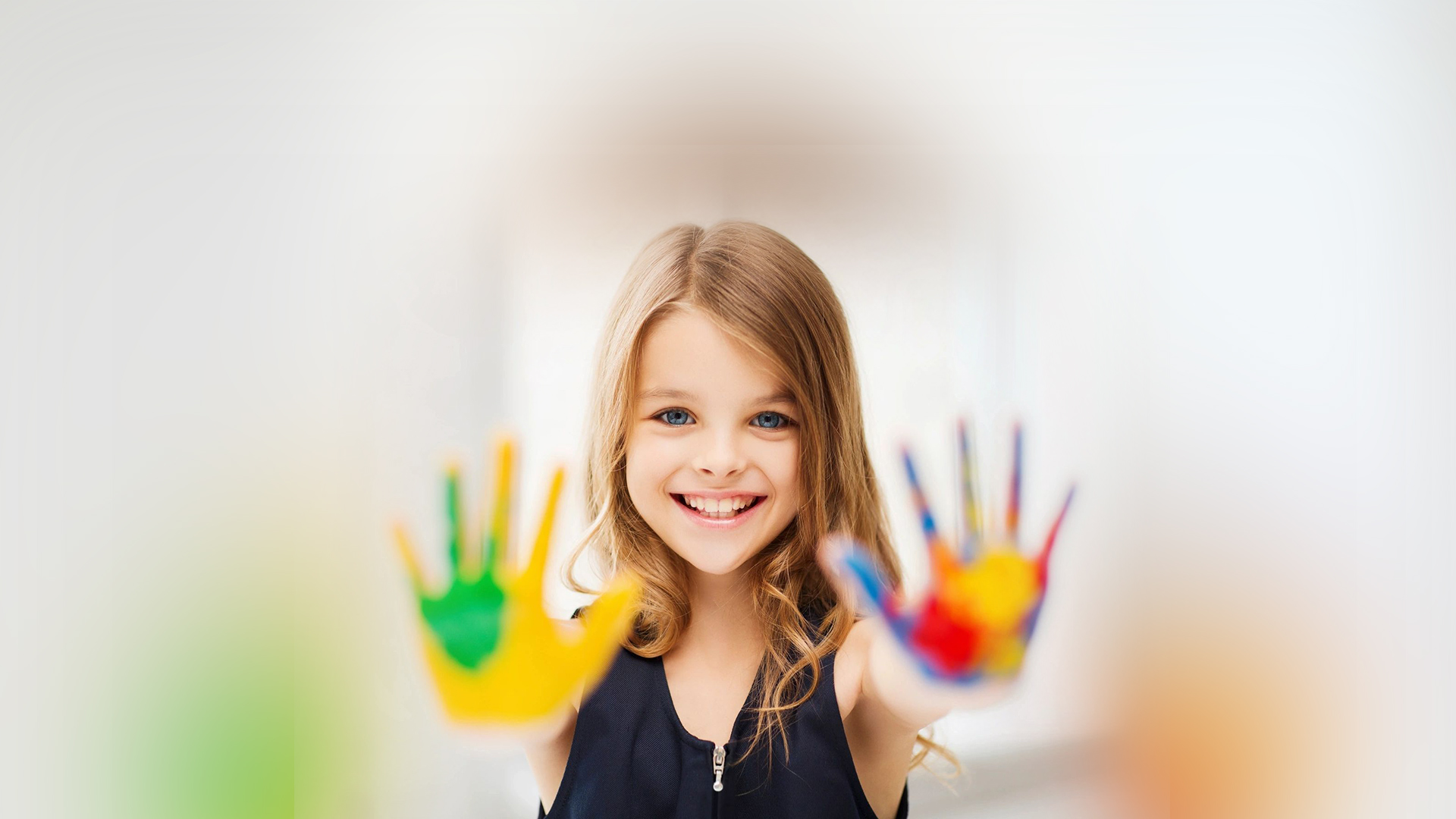 A little girl with her hands painted in the colors of rainbow.